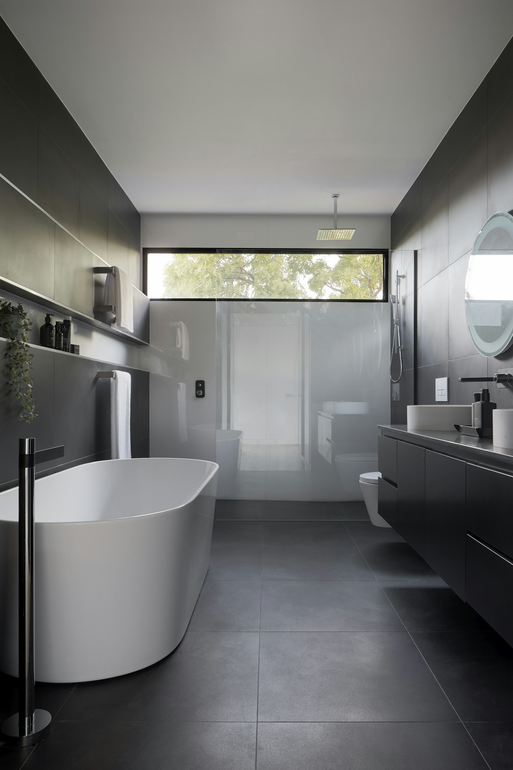 Private stone-toned bathroom with a freestanding bath and soft natural window light